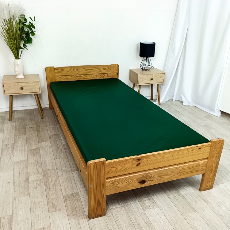 prześcieradło satynowe atłas, zieleń butelkowa rozłożone na łóżku